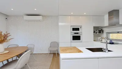 a kitchen with white cabinets and a table and chairs at Villa Barinel by Cleverdetails located in a quiet and privileged area of Vilamoura in Quarteira