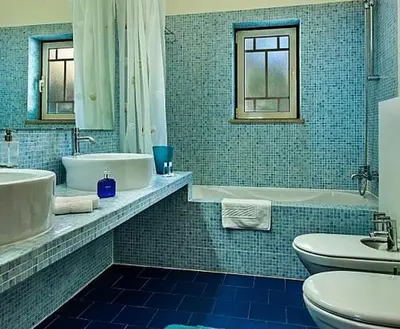a blue tiled bathroom with a tub and a toilet and a sink at Stunning home with nice pool in Albufeira