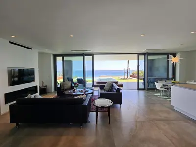 a living room with black furniture and a view of the ocean at Finisterra Deluxe in Albufeira