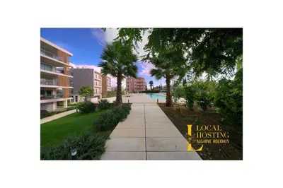 a sidewalk with palm trees next to a building at Flat Green Garden by Localhosting in Albufeira