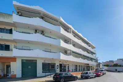 an apartment building with cars parked in front of it at Apartamento Norte by Férias com Sol in Quarteira