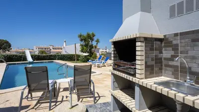 a outdoor kitchen with a grill next to a swimming pool at Greice Homes - Villa Vieira in Quarteira