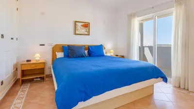 a bedroom with a bed with blue sheets and a window at Greice Homes - Villa Vieira in Quarteira