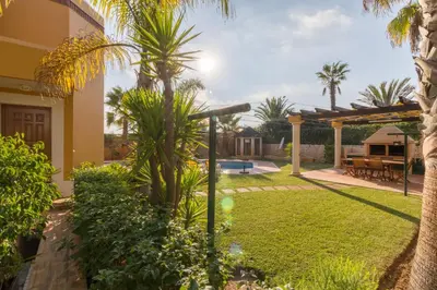 a garden with palm trees and a house at Vivenda Alegria in Albufeira
