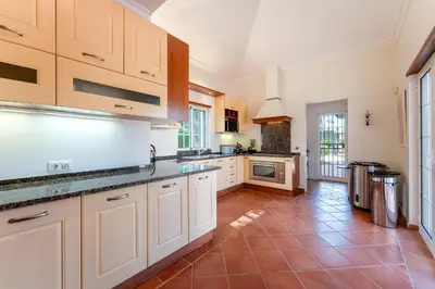 a large kitchen with white cabinets and a tile floor at Villa Serena in Almancil