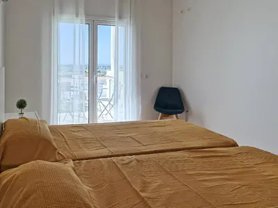 a bedroom with a bed and a chair and a window at Casa Ferreira - Encosta Vista Salgados - BY BEDZY in Guia
