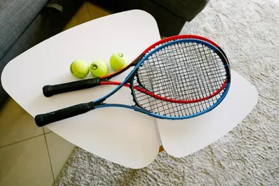 a tennis racket and four tennis balls on a bench at E Orada sea view historic center tennis in Albufeira