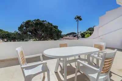 a white dining table and chairs on a balcony at Apartamentos Valverde - Quinta do Lago in Quinta do Lago