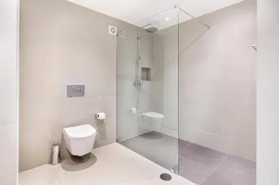 a bathroom with a toilet and a glass shower at Apartamentos Valverde - Quinta do Lago in Quinta do Lago