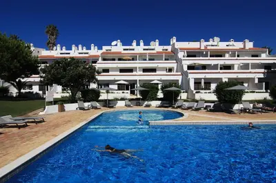 a person swimming in a swimming pool in front of a building at Apartamentos Valverde - Quinta do Lago in Quinta do Lago