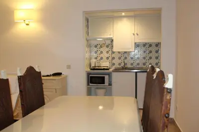 a kitchen with a white table and chairs and a counter at Cheerfulway Minichoro Apartamentos in Albufeira