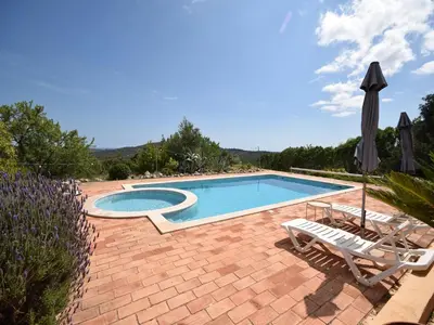 a swimming pool with two chairs and an umbrella at Elegant Loulé Mansion with Pool in Loulé