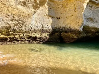 a body of water next to a rocky cliff at Albufeira Oldtown 330ft Beach Parking AC Wifi in Albufeira