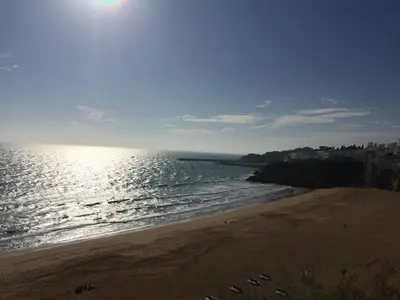 a beach with the sun shining on the water at Albufeira Oldtown 330ft Beach Parking AC Wifi in Albufeira