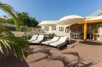 a patio with white lounge chairs and an umbrella at D_Loft Sea and Golf in Albufeira