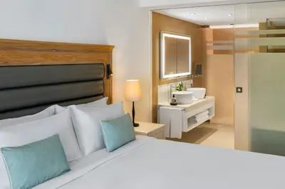 a bedroom with a white bed and a living room at Pine Cliffs Ocean Suites, a Luxury Collection Resort & Spa, Algarve in Albufeira