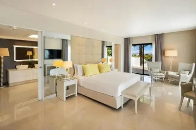 a bedroom with a large bed and a living room at Pine Cliffs Ocean Suites, a Luxury Collection Resort & Spa, Algarve in Albufeira