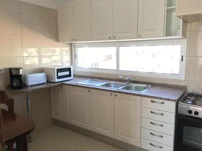 a kitchen with white cabinets and a sink and a window at Vila Praia Apartment in Albufeira