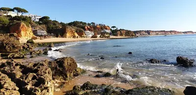 a beach with rocks and the ocean with people in the water at Villa Summertime - Private Jacuzzi and bikes, beach 800m in Albufeira