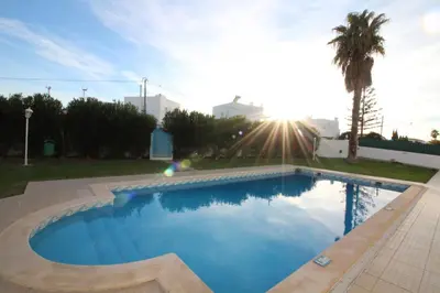 a swimming pool in a yard with the sun setting at Villa Summertime - Private Jacuzzi and bikes, beach 800m in Albufeira