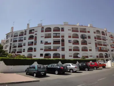 a large white building with cars parked in a parking lot at Vista Mar Apartamento in Albufeira