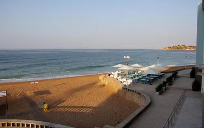 a beach with umbrellas and chairs and the ocean at INATEL Albufeira in Albufeira