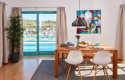 a dining room with a table and chairs and a pool at Apartment Orada Marina in Albufeira