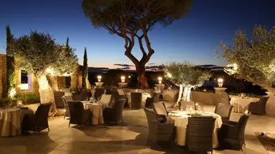 a restaurant with white tables and chairs and trees at Blue&Greens Apartment in Quinta do Lago