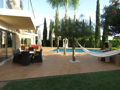 a hammock on a patio next to a pool at Villa Laguna Golf-Frente ao laguna Golf in Vilamoura
