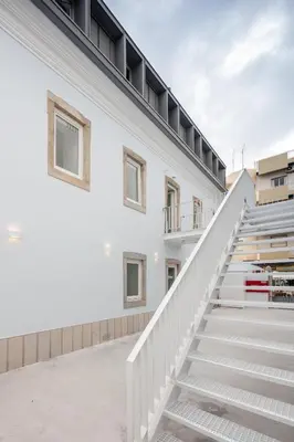 a white building with stairs on the side at Hostel Conii & Suites Algarve in Quarteira