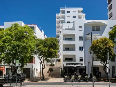 a tall white building with trees in front of it at Akisol Quarteira Relax III in Quarteira