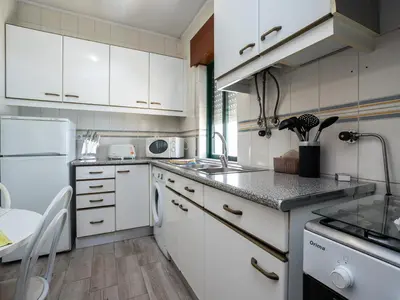 a white kitchen with a sink and a refrigerator at Akisol Quarteira Relax III in Quarteira