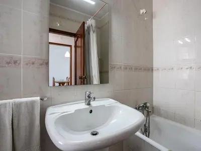 a bathroom with a sink and a tub and a mirror at Akisol Quarteira Relax III in Quarteira