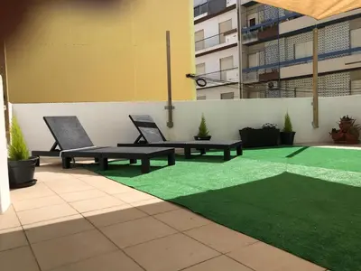 a patio with two benches and a green lawn at MariaHouse in Faro