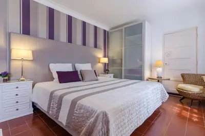 a bedroom with a large bed and a chair at Villa Casa do Sul in Albufeira