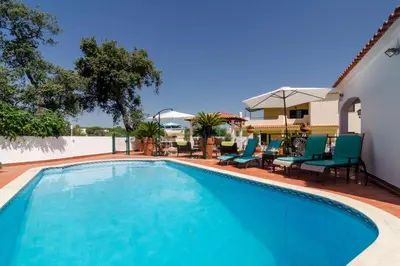 a swimming pool with blue chairs next to a house at Villa Casa do Sul in Albufeira