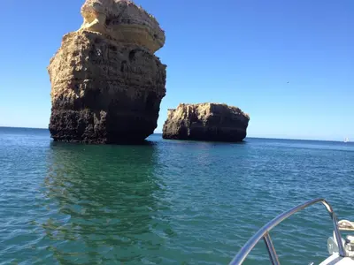 a rock formation in the water next to a boat at Vista das Ondas Apartamento 205 B2 - Olhos de Agua in Albufeira