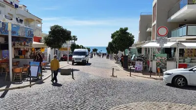 a man walking down a street with a white van at Vista das Ondas Apartamento 205 B2 - Olhos de Agua in Albufeira