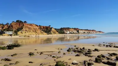 a beach with rocks in the sand and the water at Vista das Ondas Apartamento 205 B2 - Olhos de Agua in Albufeira