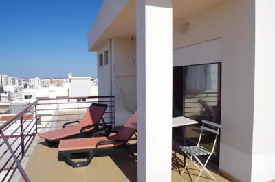 a balcony with chairs and tables on a building at BellaVita City Faro in Faro