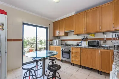 a kitchen with wooden cabinets and a table with stools at BellaVita City Faro in Faro