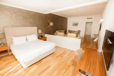 a bedroom with a white bed and a living room at Vilamoura Garden Hotel in Vilamoura