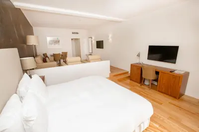 a bedroom with a white bed and a living room at Vilamoura Garden Hotel in Vilamoura