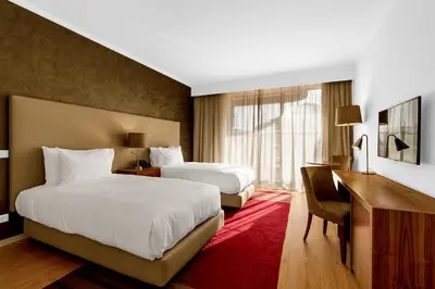 a hotel room with two beds and a desk at Vilamoura Garden Hotel in Vilamoura