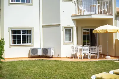 a patio with a table and chairs and an umbrella at Vila do Castelo in Albufeira
