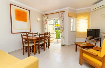 a living room with a table and chairs and a television at Vila do Castelo in Albufeira