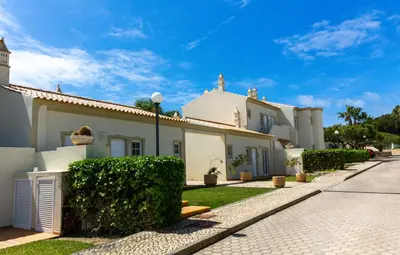 a large white house with bushes in front of a street at Vila do Castelo in Albufeira