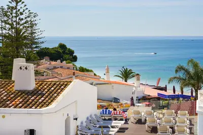a view of a resort with chairs and the ocean at 3HB Golden Beach in Albufeira