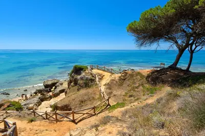 a beach with blue and white chairs and the ocean at Luna Miramar Club in Albufeira