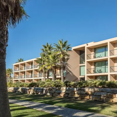 a bedroom with a large white bed and a chair at Kimpton Atlantico Algarve by IHG in Albufeira